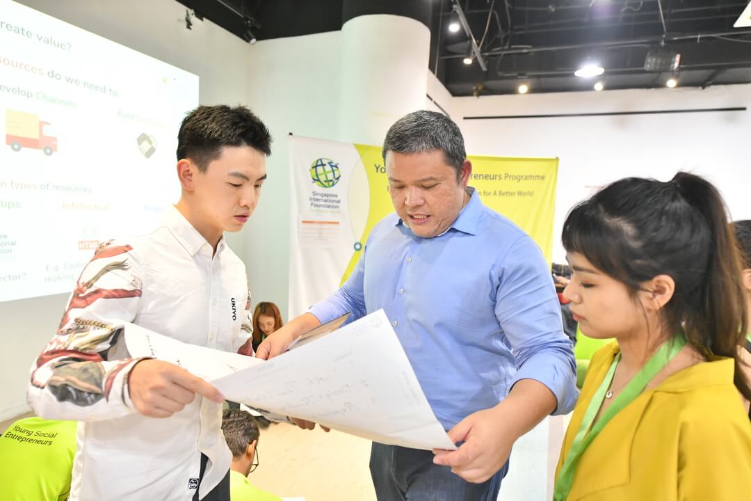 Russ Neu, Founder and CEO of Social Collider from Singapore works with team Peach Talk (China) at a Social Enterprise Marketplace where YSEs learnt ways to leverage shared resources to advance the growth of their SEs
